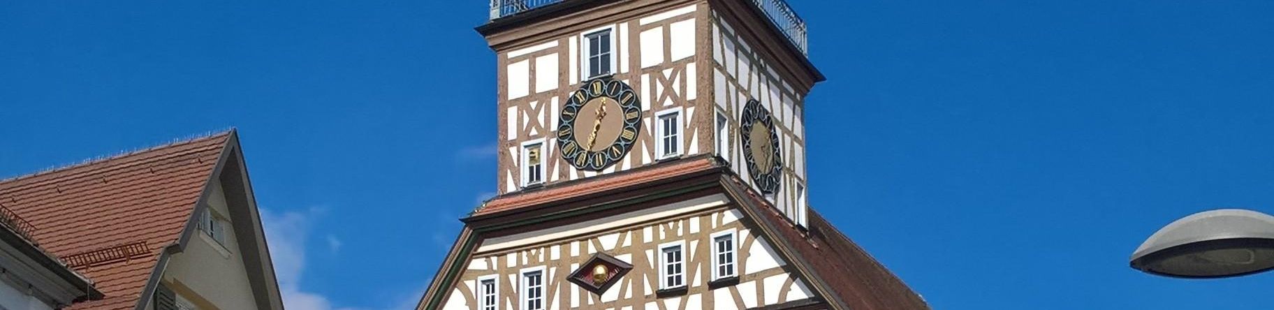 Fachwerk-Rathaus mit Uhrturm und Menschen auf dem Marktplatz