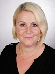 Lächelnde Frau mit kurzem blondem Haar und schwarzem Oberteil